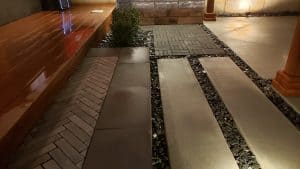 a small outdoor living space with patio pavers and hardscape design at night